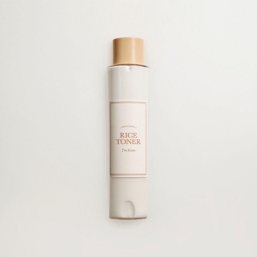 Flacone di tonico al riso, beige e bianco, con tappo color oro.