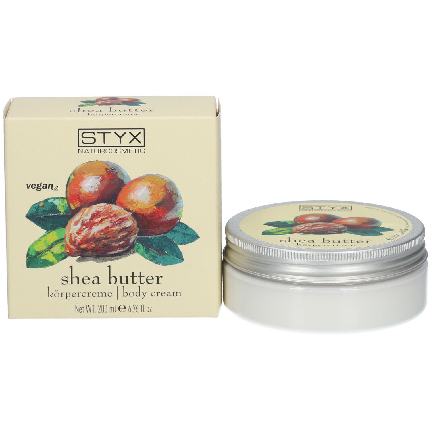 Barattolo di crema e scatola. Sul barattolo e sulla scatola: STYX, crema corpo al burro di karité. Scatola con illustrazione di noci di karité e foglie.