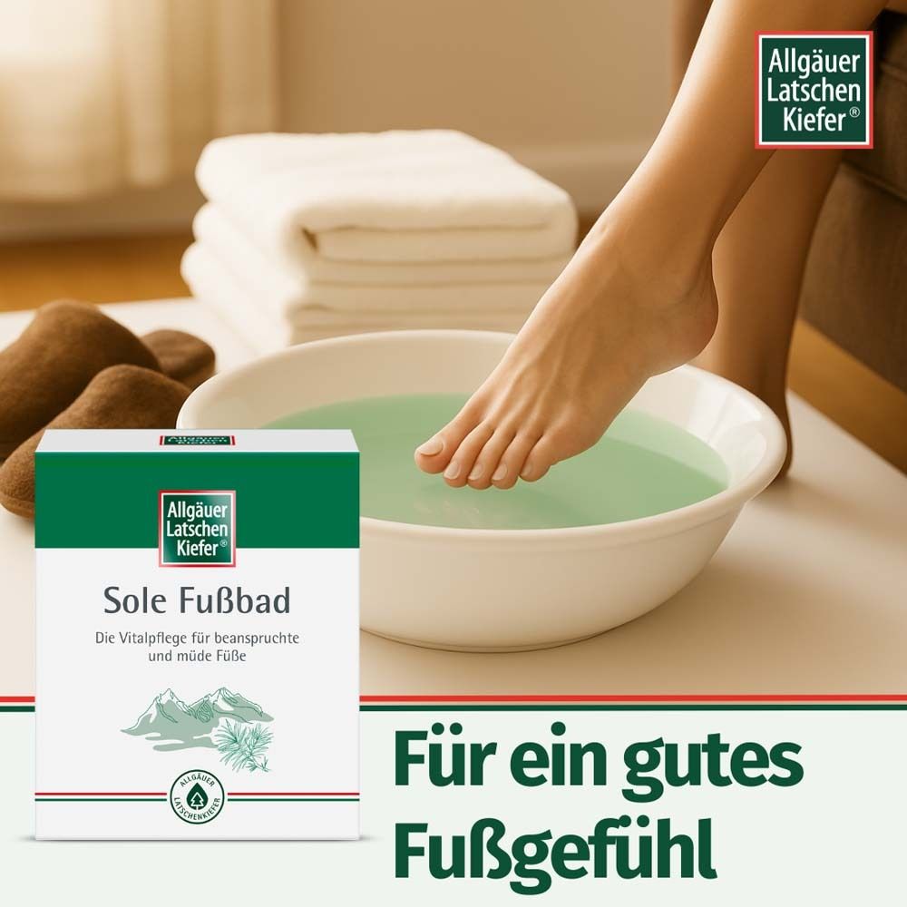 Piede in una bacinella con pediluvio. Confezione Allgäuer Latschenkiefer Sole Fußbad accanto. Asciugamani e pantofole.