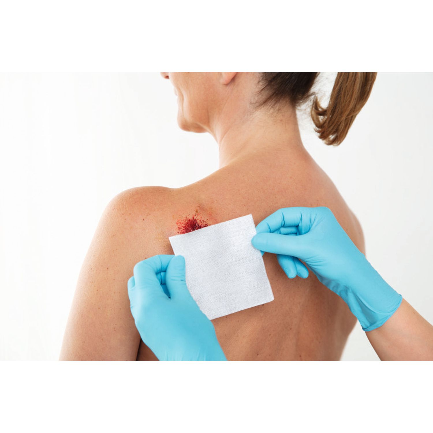 Persona con guanti applica Fixomull® stretch su una ferita sulla schiena.