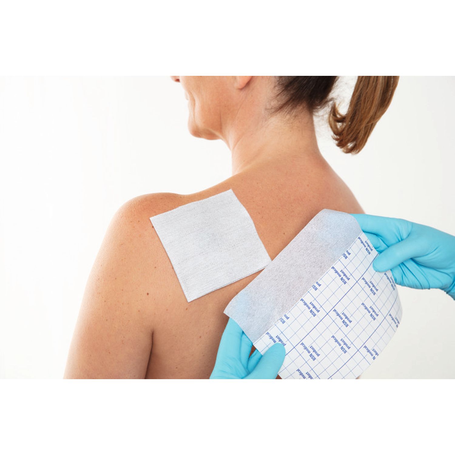 Fixomull® stretch applicato su una ferita sulla schiena. Mani con guanti.