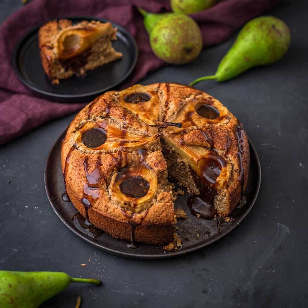 Torta con pere e salsa al cioccolato. Su un piatto nero, decorata con pere.