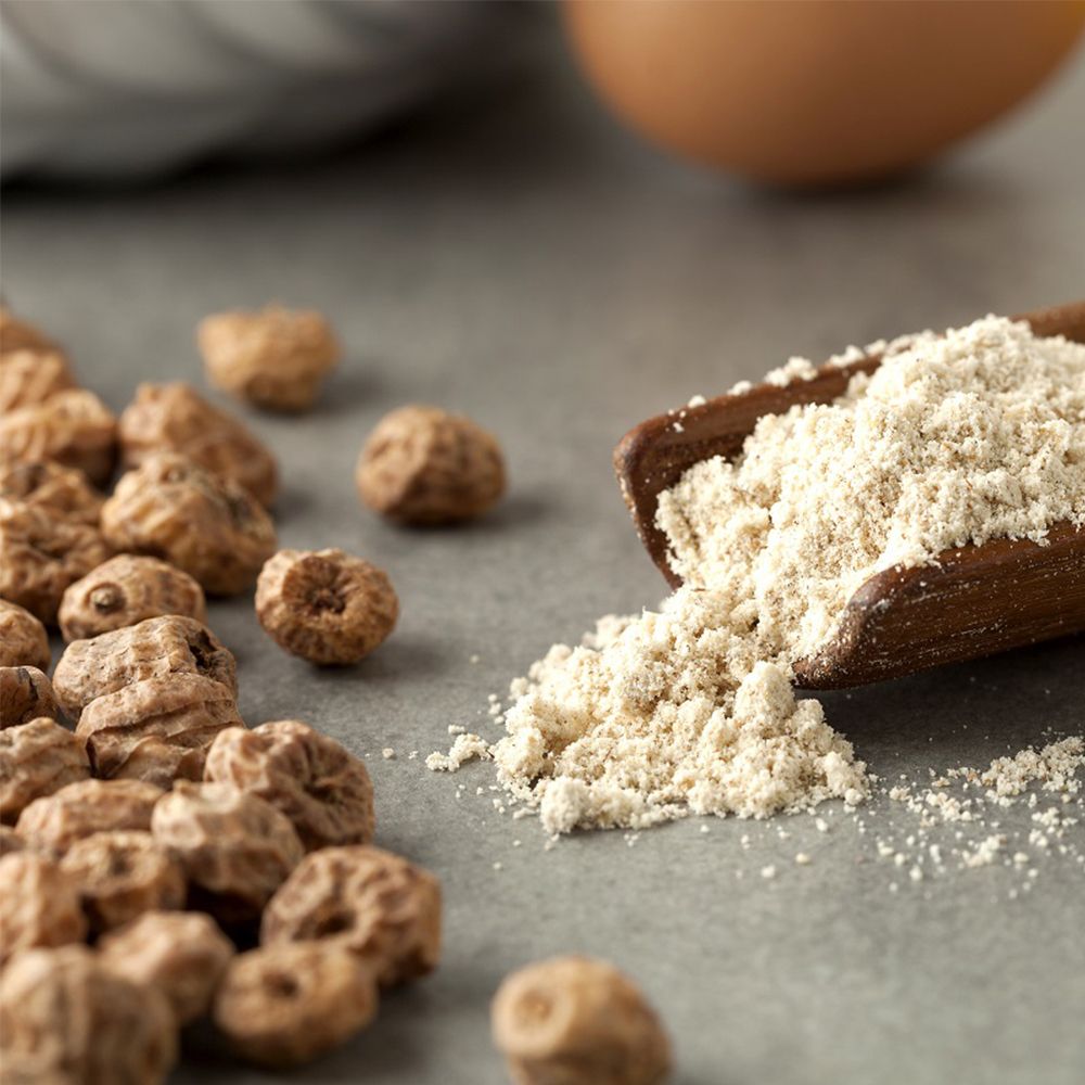 Farina di zigolo dolce in una paletta di legno. Accanto, zigoli dolci. Su sfondo grigio.