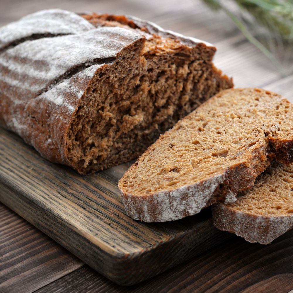 Pane a fette su un tagliere di legno. Crosta scura, mollica chiara. Affettato.