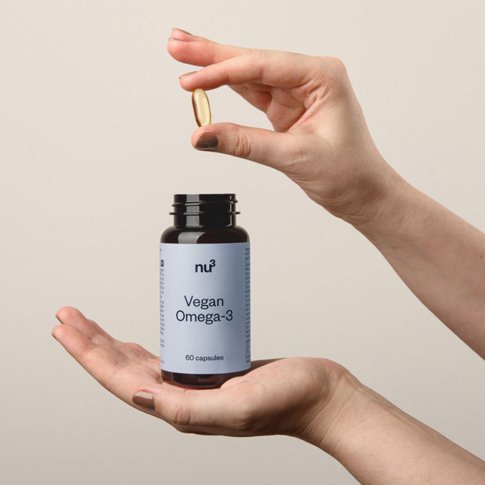 Mani che tengono una capsula sopra una bottiglia. Scritta: nu3 Vegan Omega-3, 60 capsule.