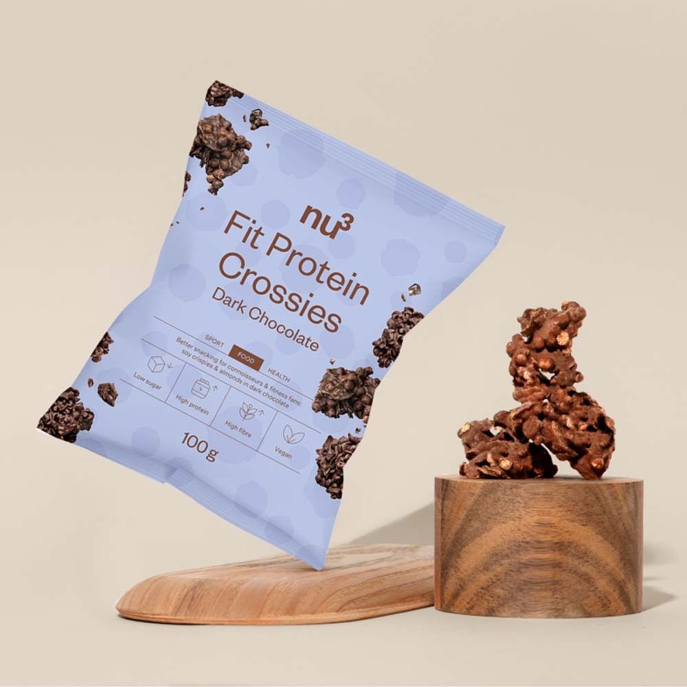 Confezione del prodotto nu3 Fit Protein Crossies, cioccolato fondente, su un piedistallo di legno. Accanto, una tavola di legno.