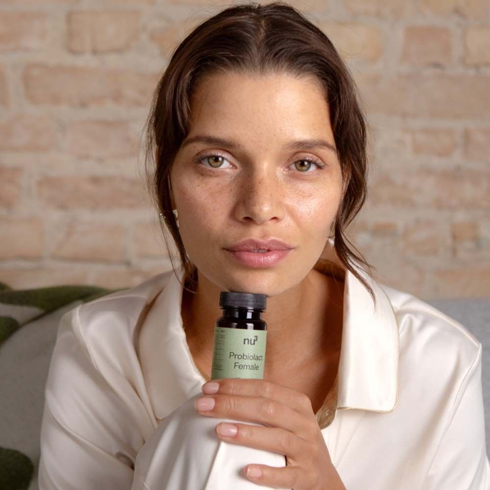 Donna che tiene in mano un flacone di « nu3 Probiolact Female ». Flacone marrone con tappo nero.