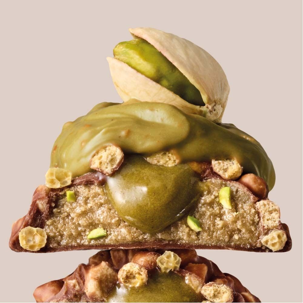 Primo piano di una barretta proteica con guarnizione ai pistacchi. Strati, pistacchi e crema visibili.
