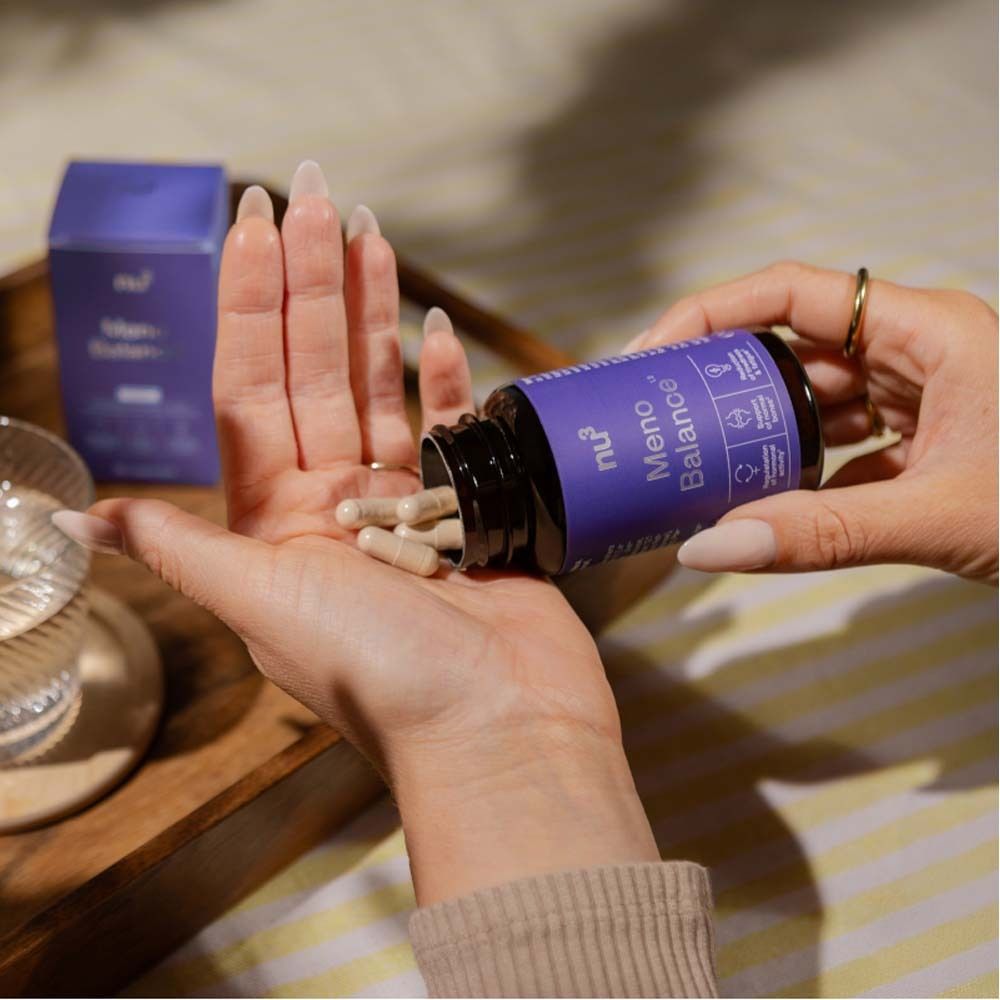 Mani che tengono capsule da un flacone. Marca: nu3 Meno Balance. Etichetta viola.