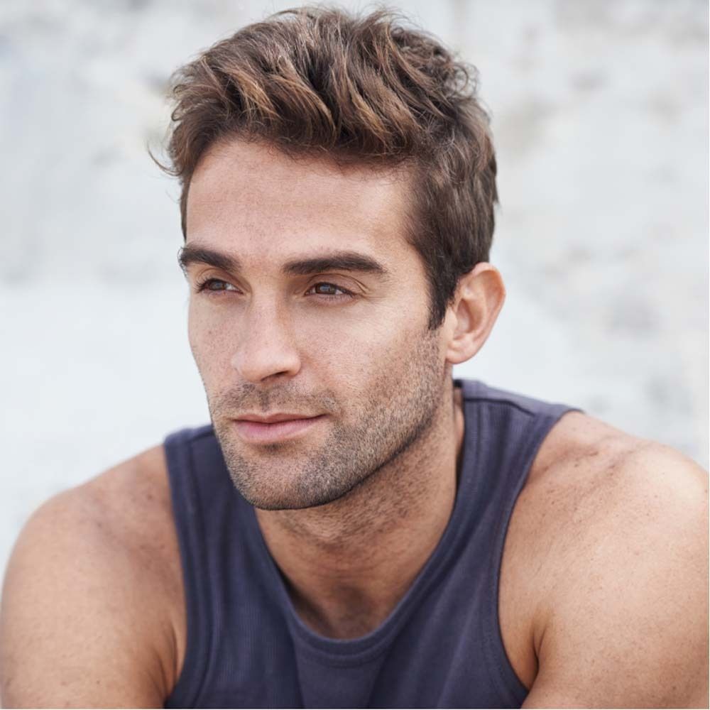 Ritratto di un uomo con capelli castani e barba. Sembra pensieroso.