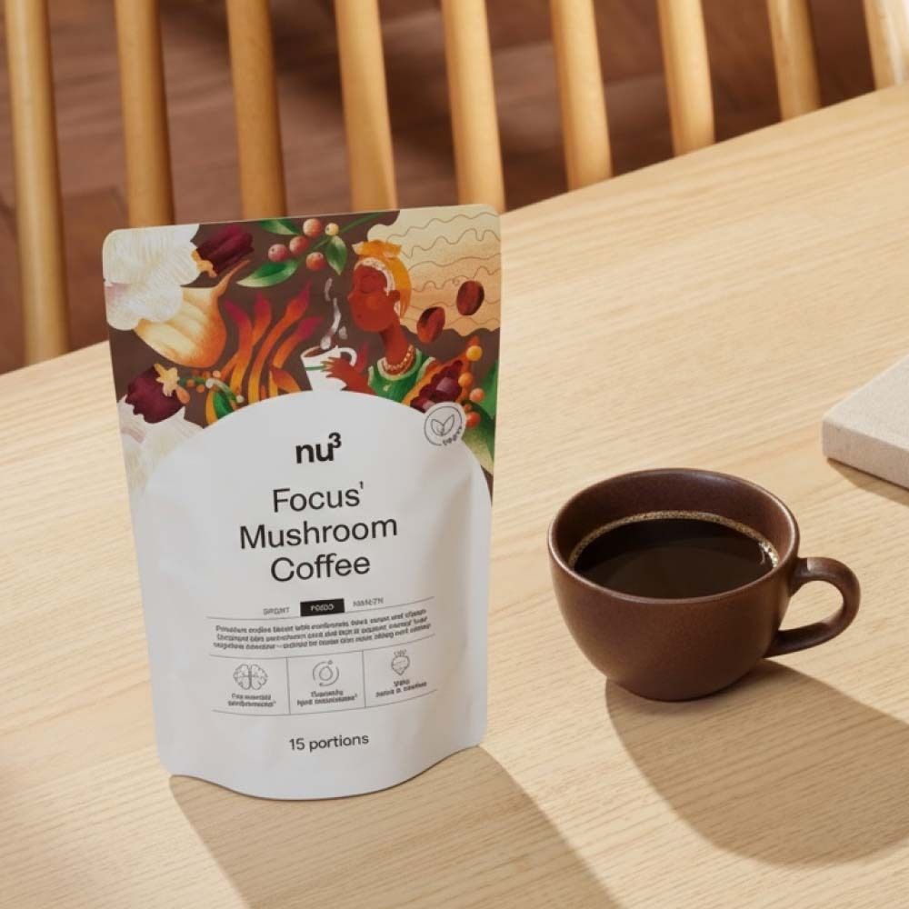 Tazza di caffè accanto alla confezione di nu3 Focus Mushroom Coffee. Su tavolo di legno.