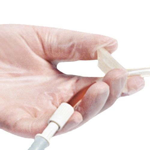 Mano con un guanto da esame in vinile. Il guanto è tenuto per la punta.