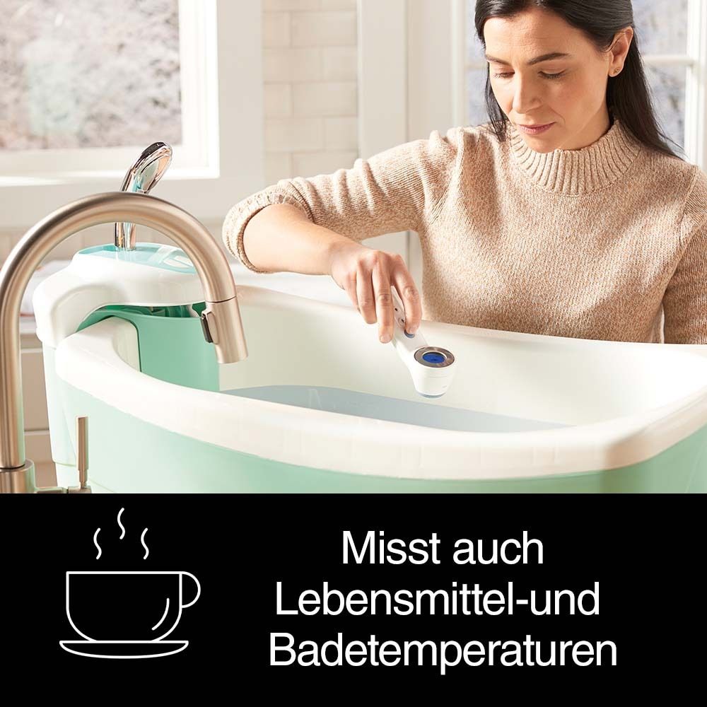 Una donna tiene un termometro nell'acqua del bagno. Il termometro è bianco e ha un pulsante blu.