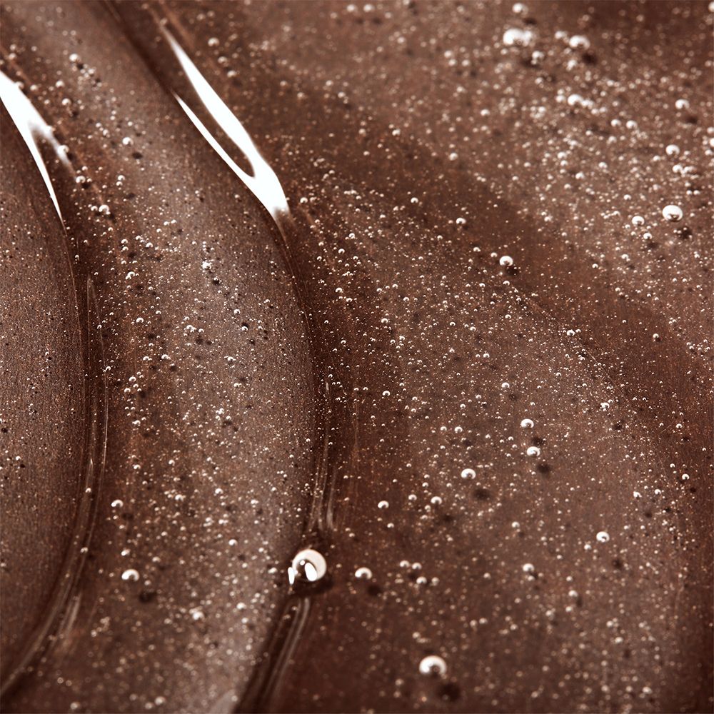 Primo piano di gel doccia marrone. La consistenza è liscia e lucida, con piccole bolle.