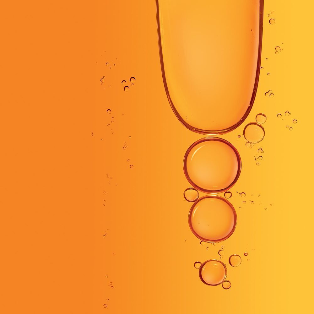 Liquido arancione con bolle d'aria. Sfondo giallo. Il liquido sembra salire.