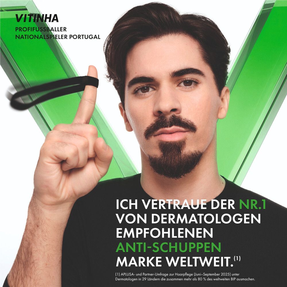 Un uomo con barba e baffi tiene un elastico per capelli nero sul dito. "Vitinha" è scritto in alto a sinistra.