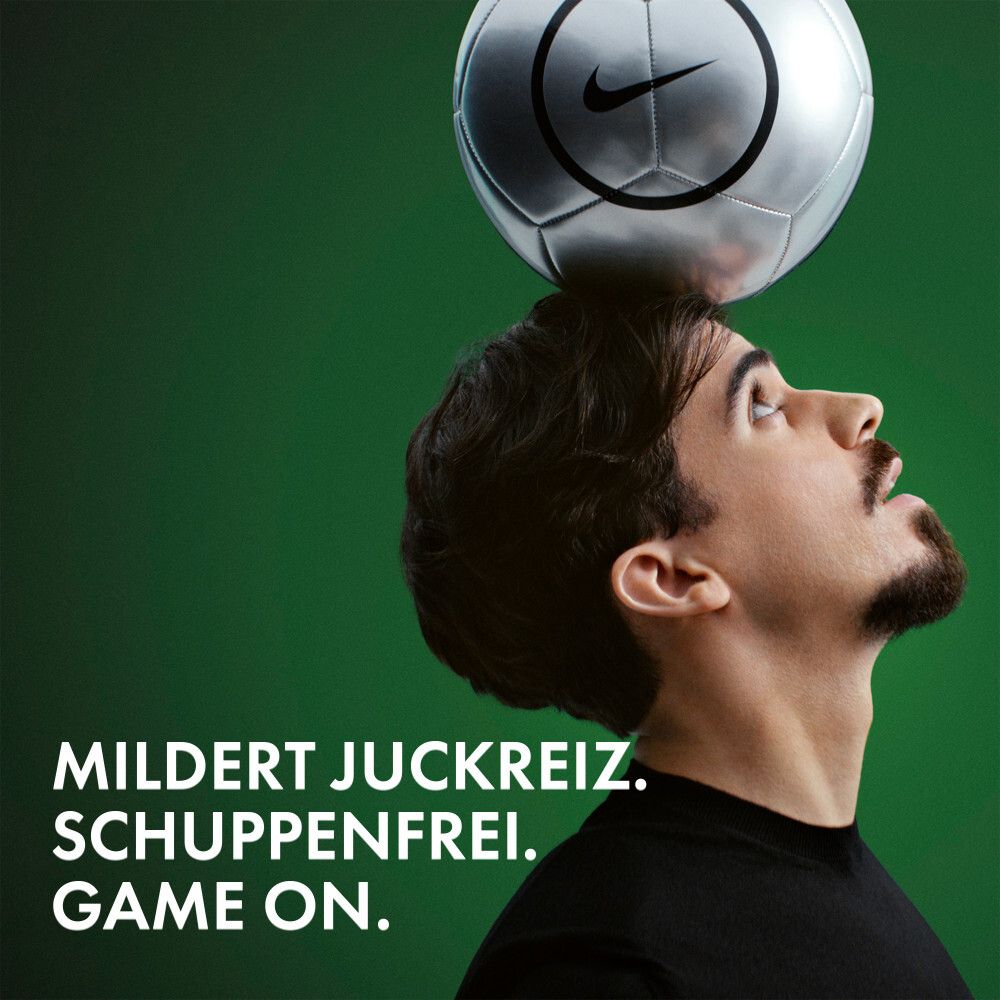 Uomo in equilibrio con pallone da calcio argentato con logo Nike sulla testa.
