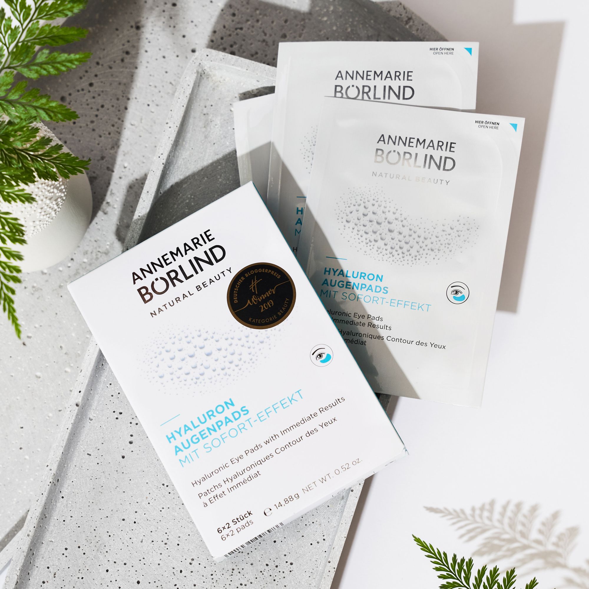 Tre confezioni di patch per occhi. Marchio: ANNEMARIE BÖRLIND. Testo: Hyaluron Augenpads mit Sofort-Effekt. Su cemento.