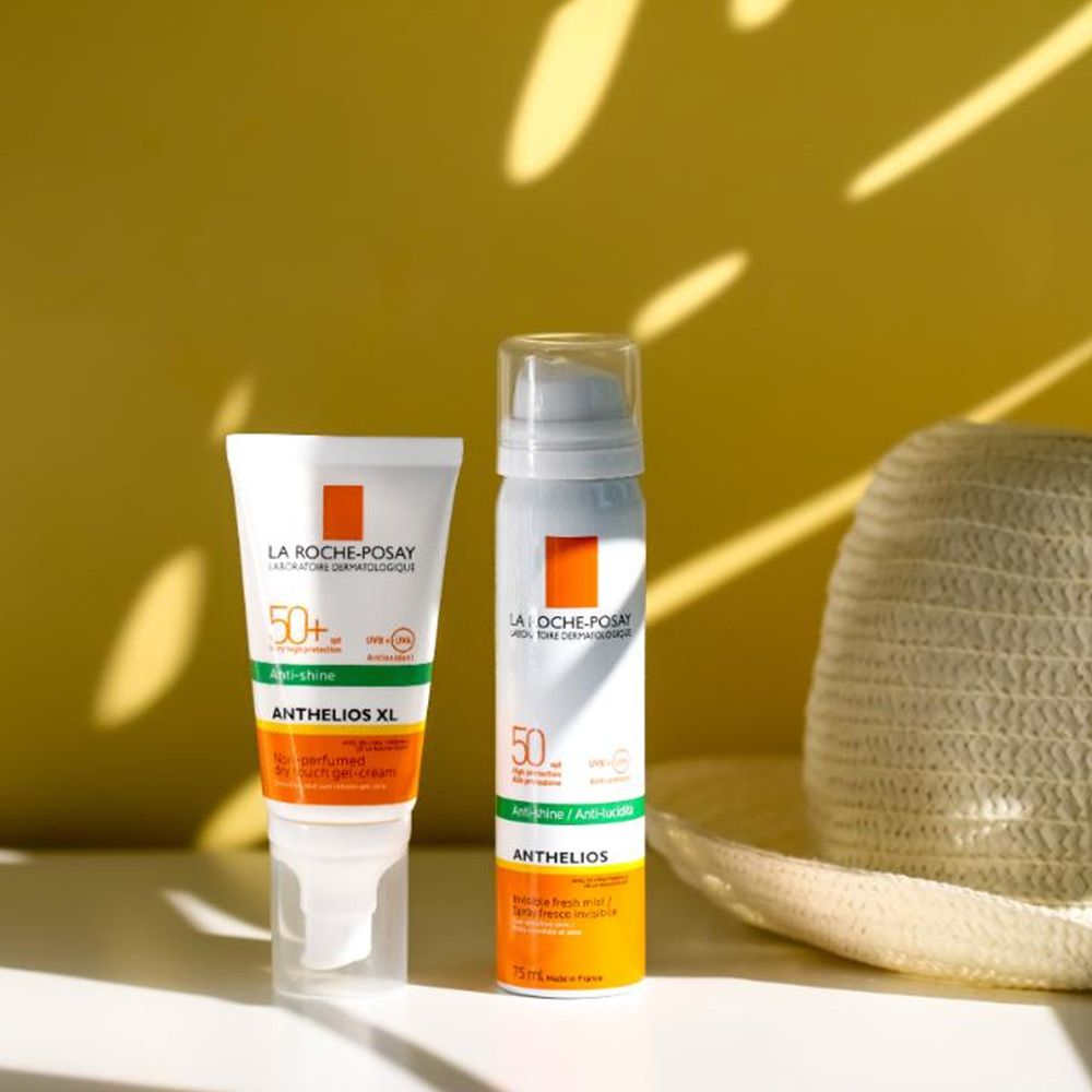 Due prodotti solari. A sinistra: tubo. A destra: spray. Bianchi, accenti arancioni. Testo: Anthelios 50+.