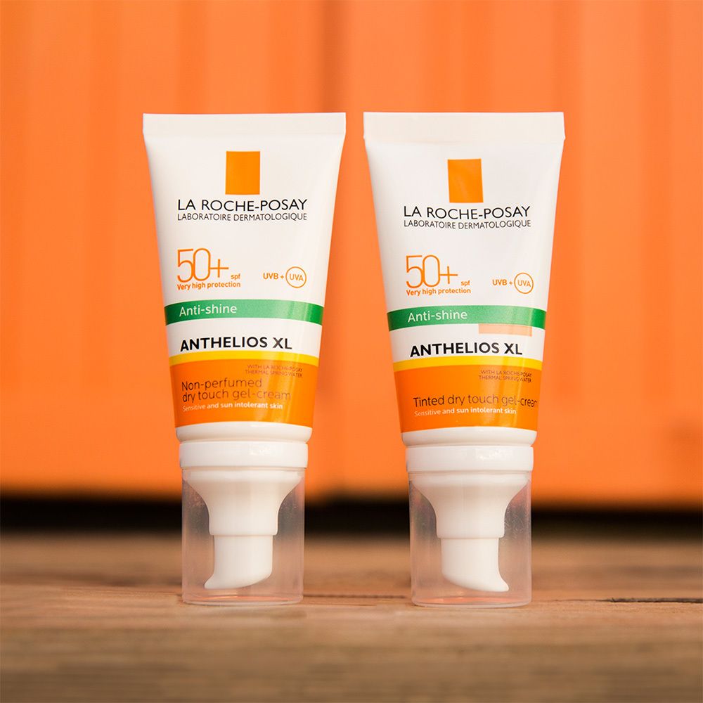 Due tubi di crema solare. Bianco, accenti arancioni e verdi. Testo: Anthelios XL 50+.
