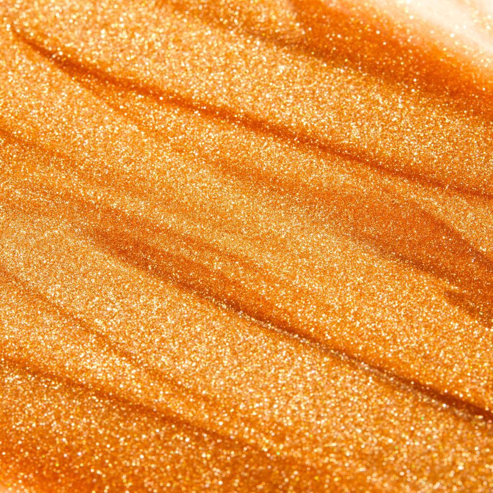 Primo piano di olio dorato scintillante. Texture ondulata con particelle brillanti.
