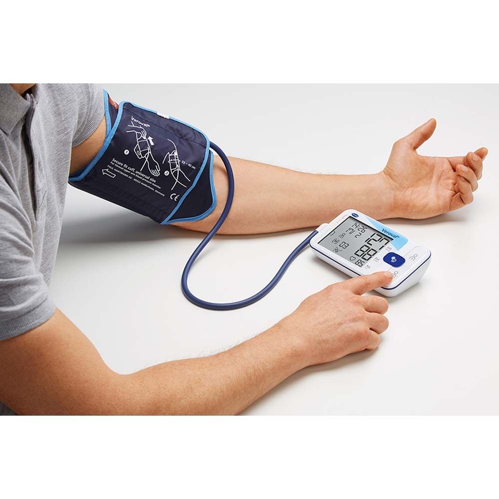 Persona misura la pressione sanguigna con dispositivo e bracciale. Ampio display con valori.