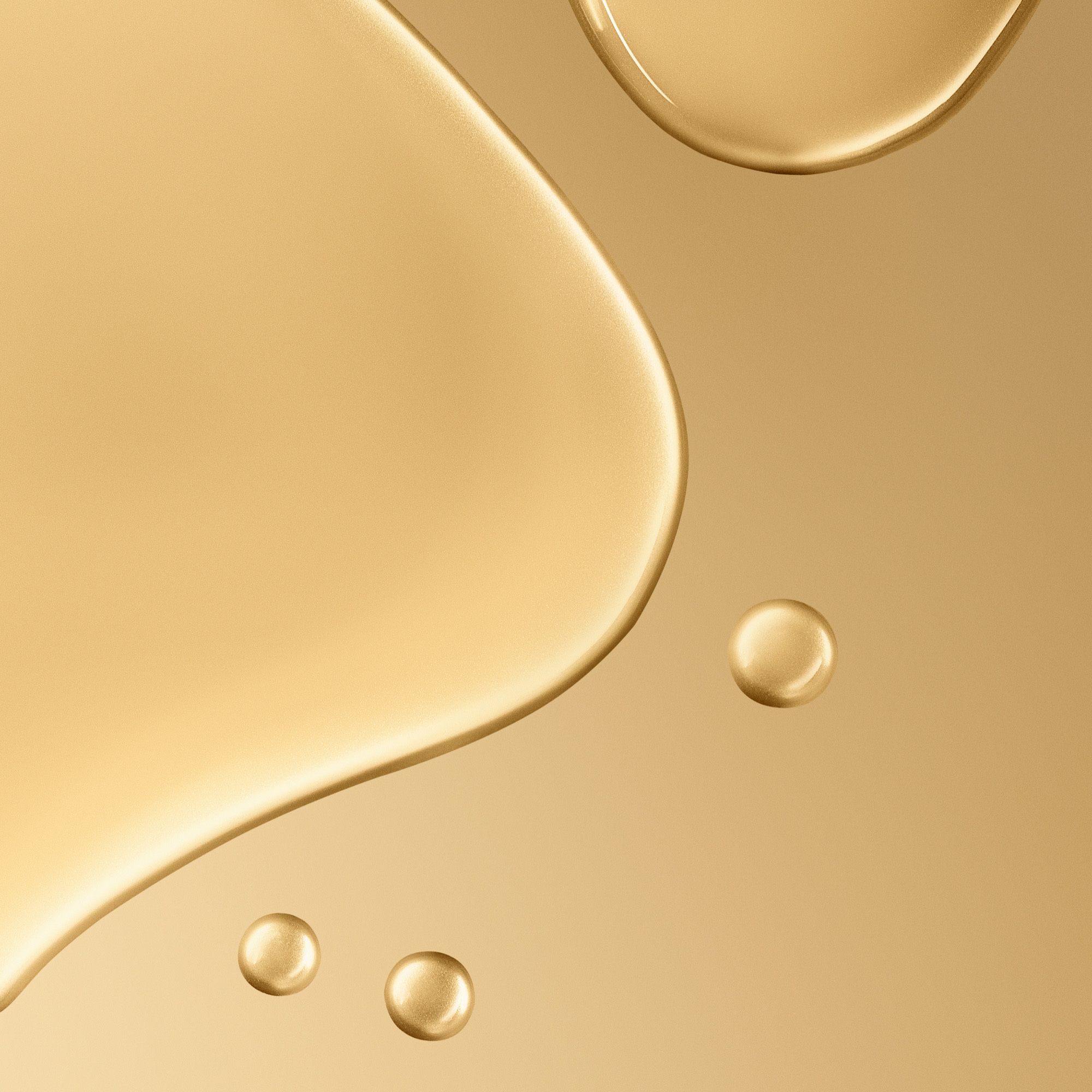 Primo piano di gocce di liquido dorato. Diverse gocce su sfondo beige.