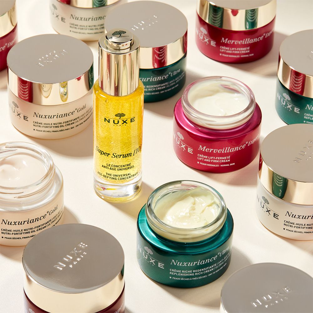 Vari prodotti cosmetici: siero, creme, vasetti. Nuxuriance Gold.