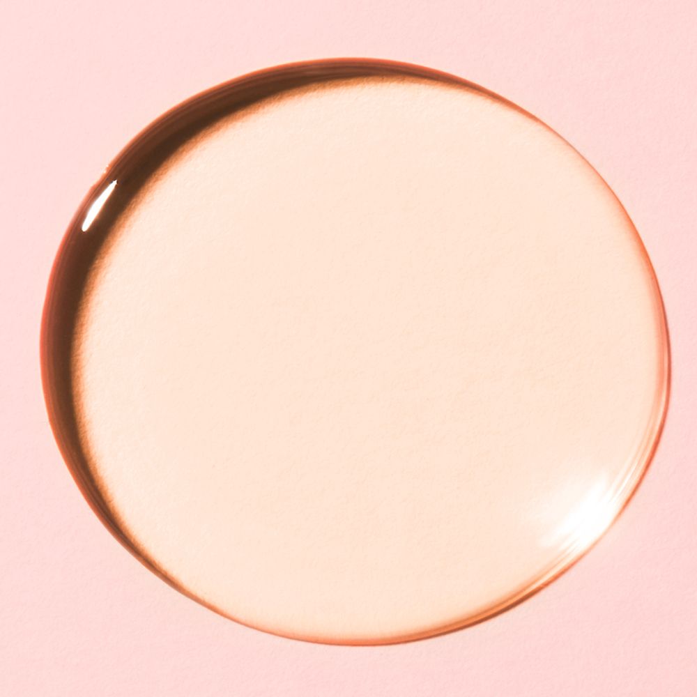 Goccia rotonda di olio su sfondo rosa. L'olio è trasparente.