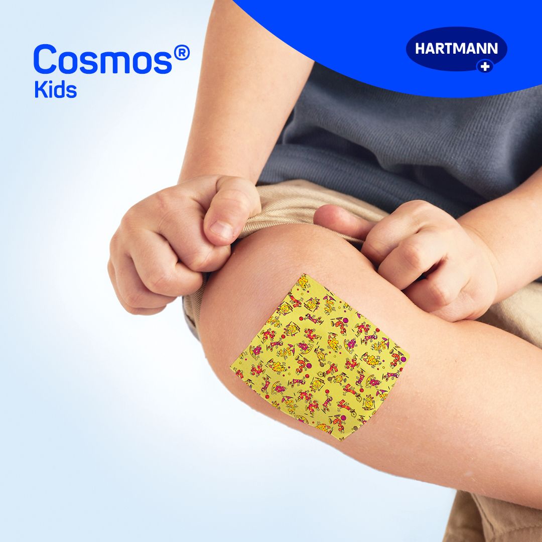 Bambino con cerotto giallo sul ginocchio. Cerotto giallo con motivi colorati. Nome del prodotto non visibile.