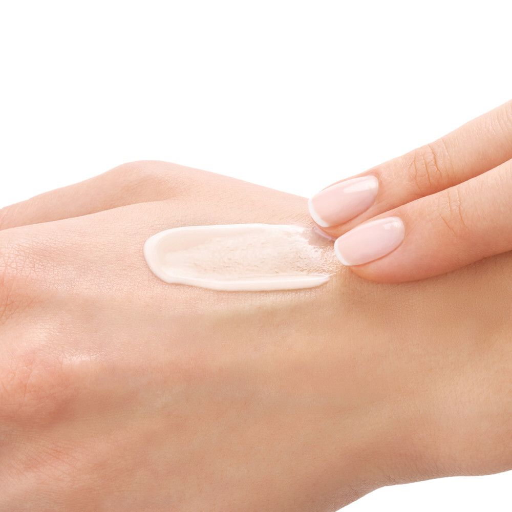 Mano con crema. Striscia di crema sulla mano. Pelle chiara, crema chiara. Unghie smaltate.