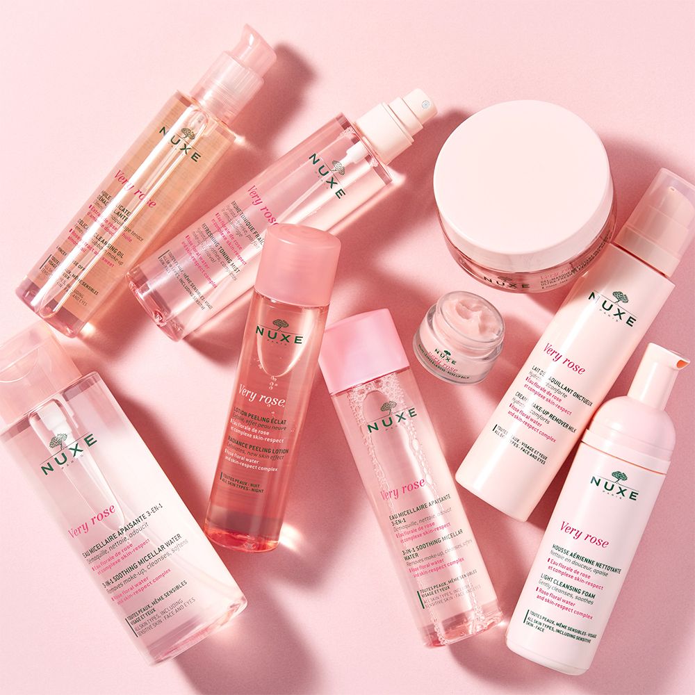 Vari prodotti NUXE Very Rose. Flaconi, vasetti e contenitori rosa. Sfondo rosa.