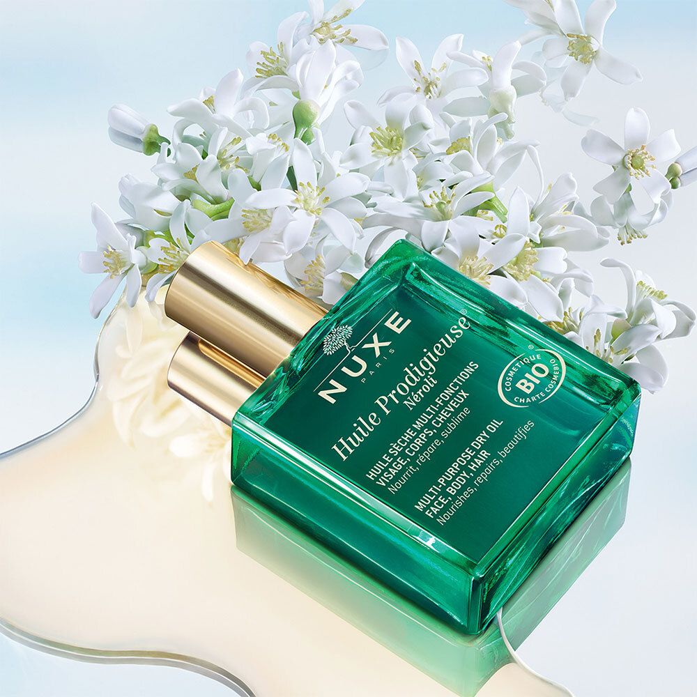 Flacone verde con tappo dorato, circondato da fiori e olio. Certificazione Bio.