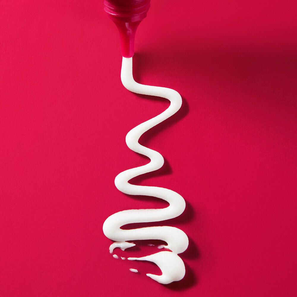 Crema bianca su sfondo rosso. La crema forma una linea sinuosa.