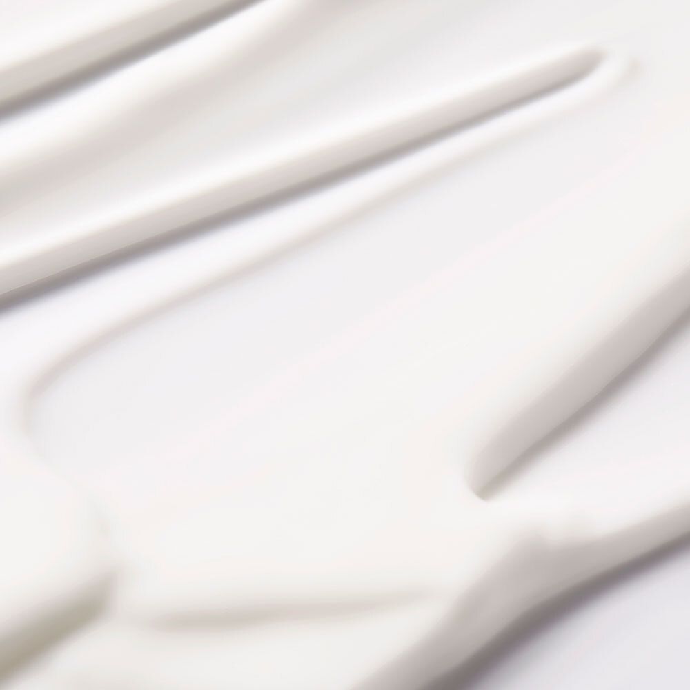 Primo piano di crema bianca. Texture della crema con linee lisce e ondulate.