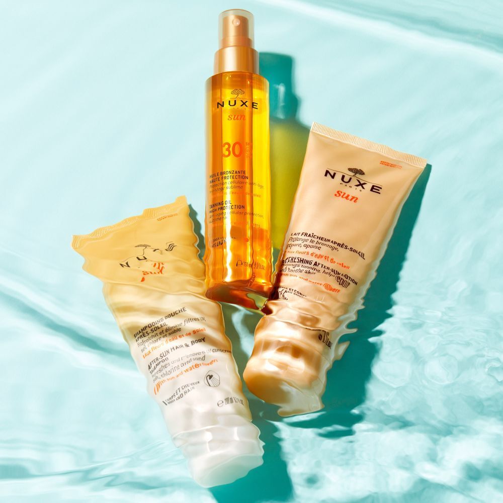Tre prodotti NUXE Sun sull'acqua blu. Tubi di crema solare e flacone spray.