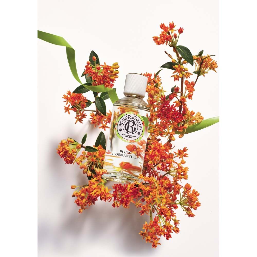 Flacone in vetro con tappo bianco, circondato da fiori arancioni. Nome prodotto: Fleur d'Osmanthus.