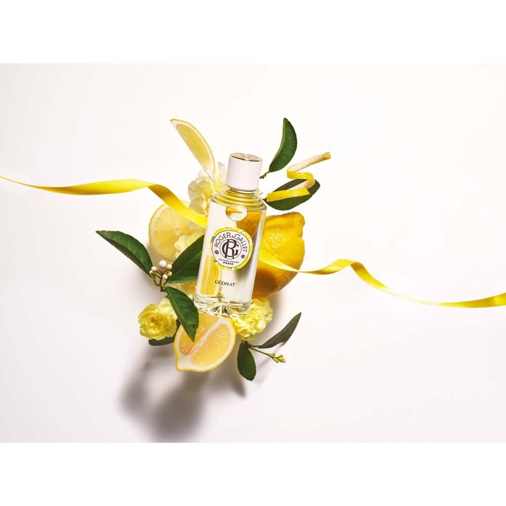 Flacone in vetro circondato da limoni, foglie e nastro giallo. Logo e scritta Cédrat.