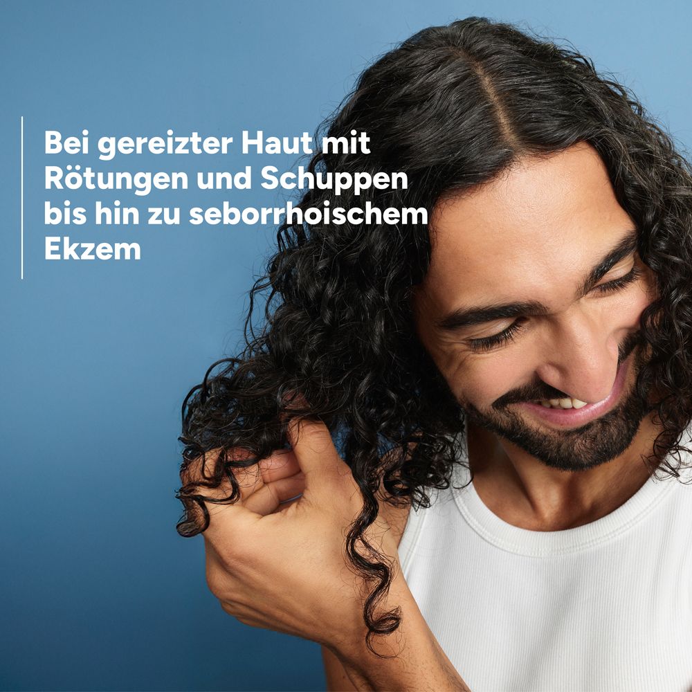 Uomo con capelli ricci si gratta la testa. Testo: Per pelle irritata con rossori e desquamazione fino all'eczema seborroico.