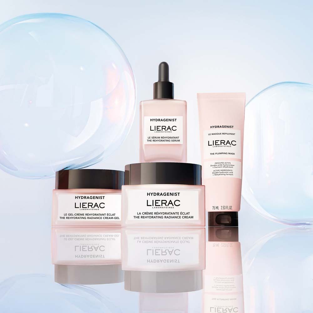 Vari prodotti LIERAC Hydragenist. Flaconi, vasetti e tubetto in rosa e bianco.