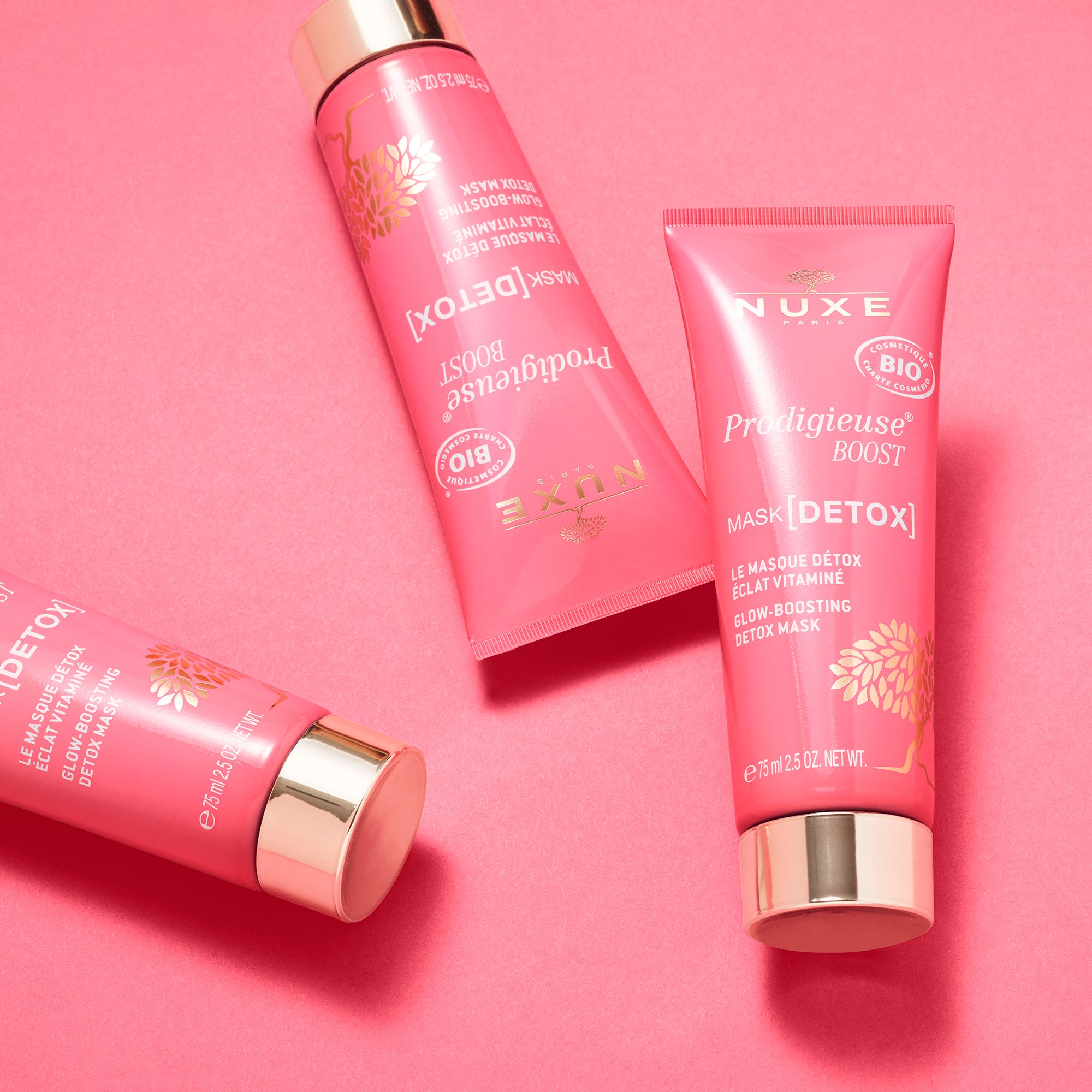 Tre tubi rosa con dettagli dorati. NUXE Prodigieuse Boost Mask [DETOX]. Su sfondo rosa.