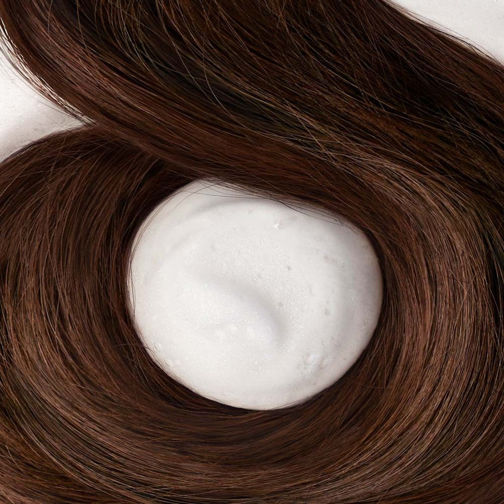 Primo piano di capelli castani con una palla di schiuma bianca al centro.