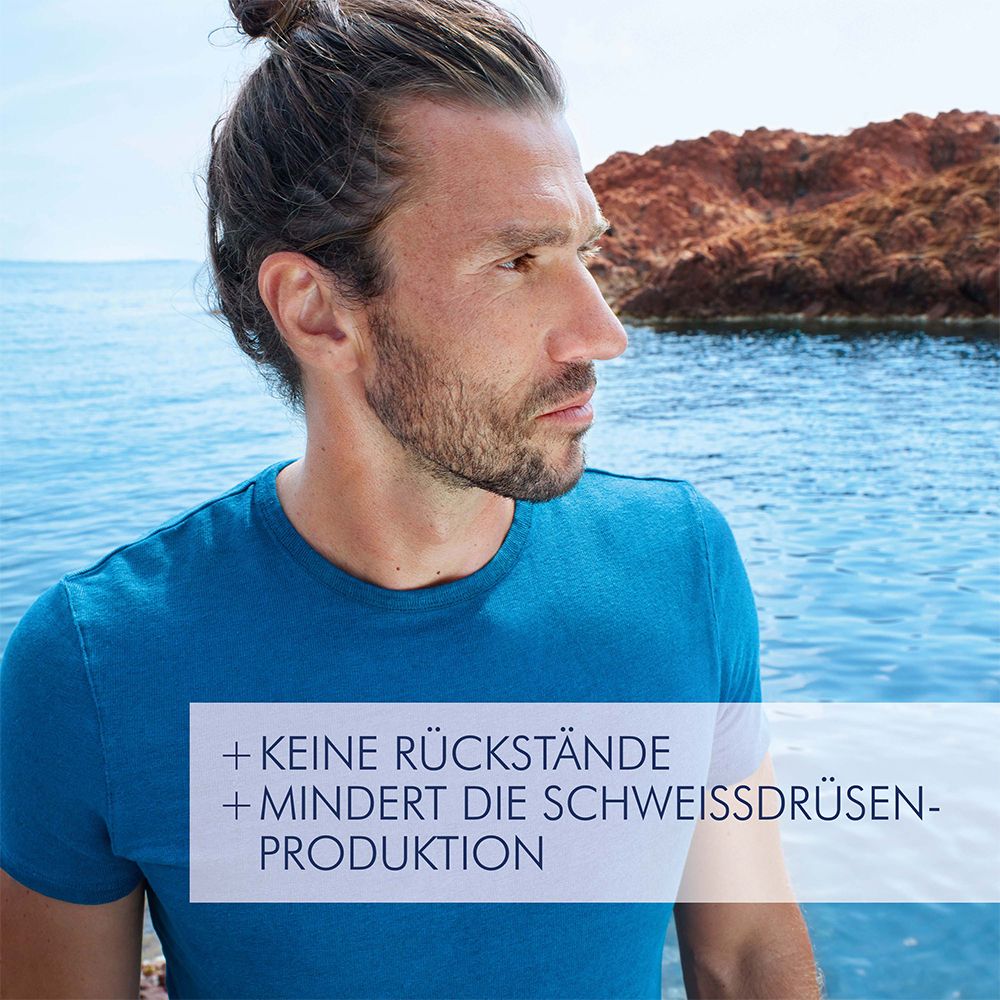 Uomo con maglietta blu in riva al mare. Testo: + NESSUN RESIDUO + RIDUCE LA PRODUZIONE DI SUDORE.