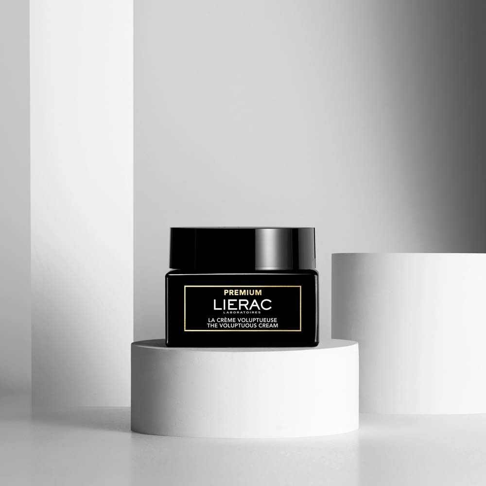 Vasetto nero con coperchio su piedistallo bianco. Scritta: PREMIUM LIERAC. Testo: LA CRÈME VOLUPTUEUSE.