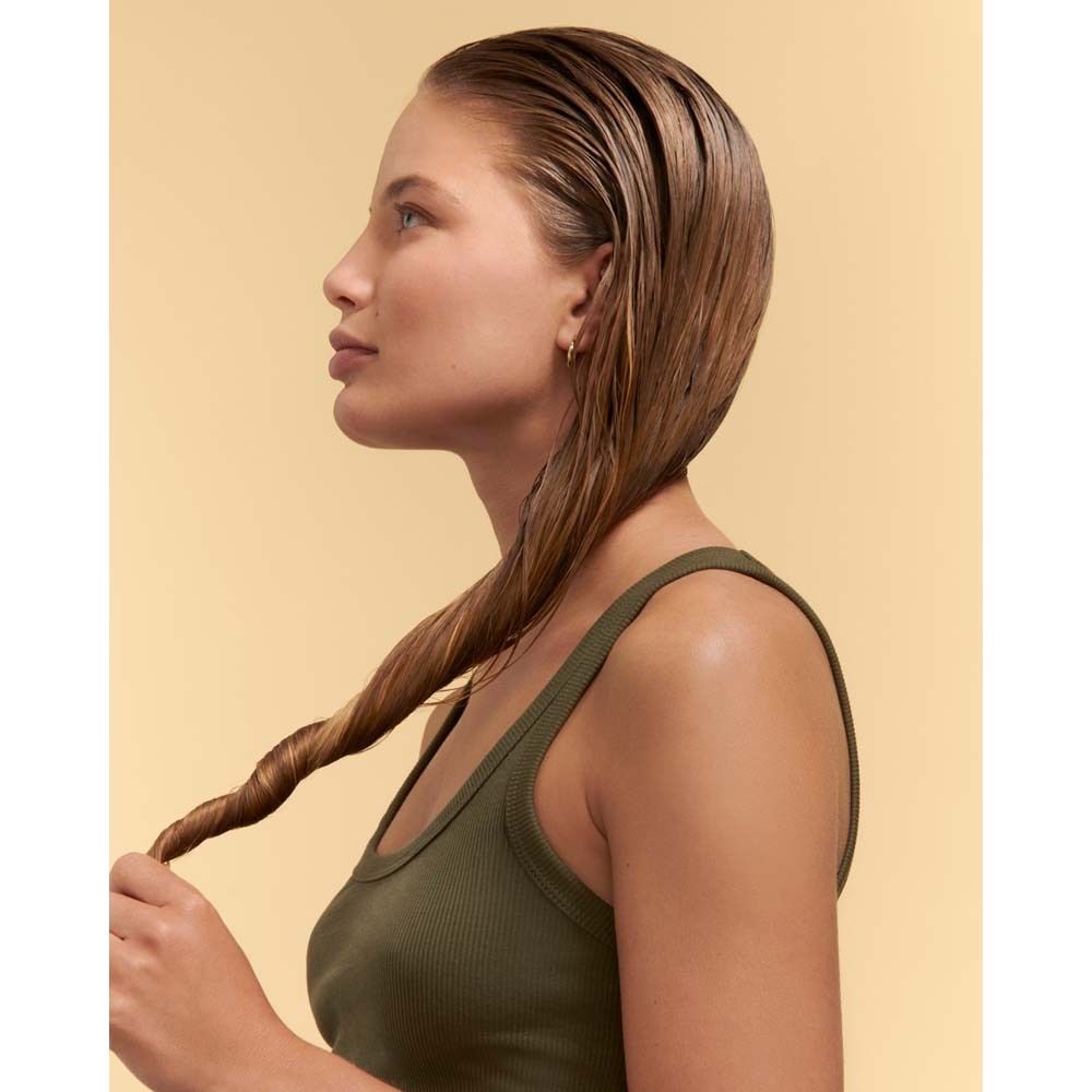 Donna con capelli bagnati, che gira una ciocca per formare una treccia.