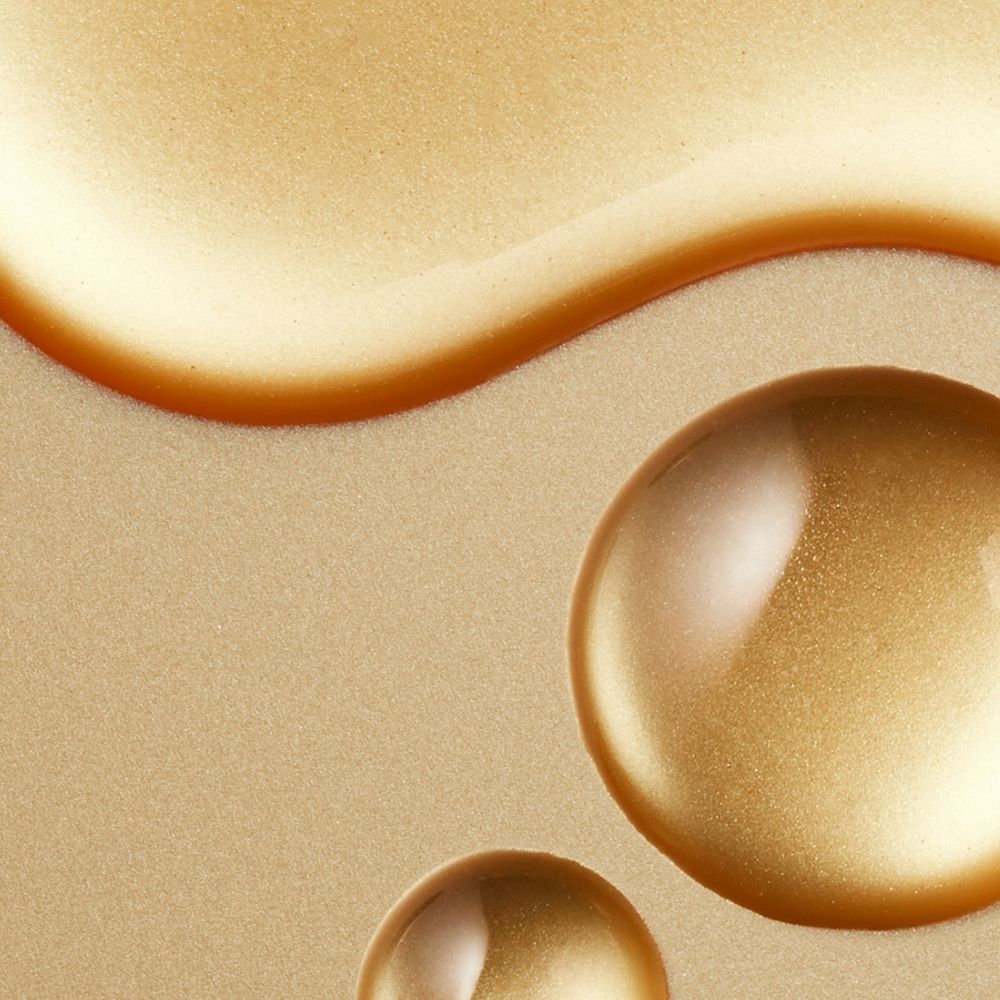 Liquido dorato, gocce. Sfondo dorato. Tre gocce dorate.