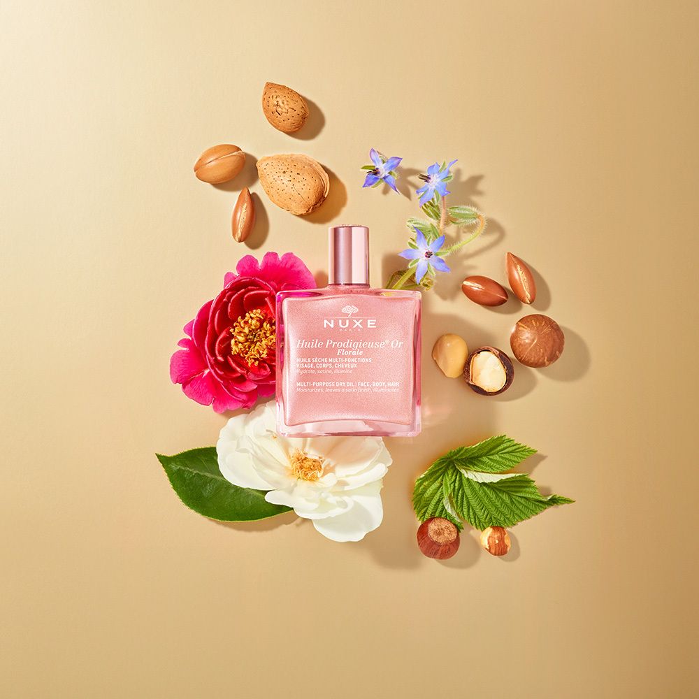 Nuxe Huile Prodigieuse® Or Florale. Flacone rosa con tappo dorato. Fiori e noci.