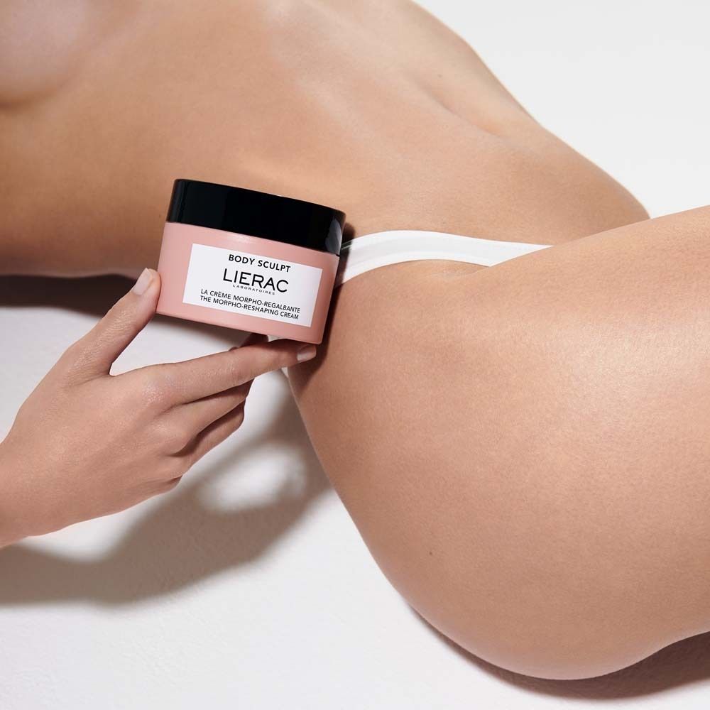 Persona che tiene un vaso rosa con coperchio nero. Scritta: BODY SCULPT, LIERAC, LA CRÈME MORPHO-REGALBANTE, THE MORPHO-RESHAPING CREAM.