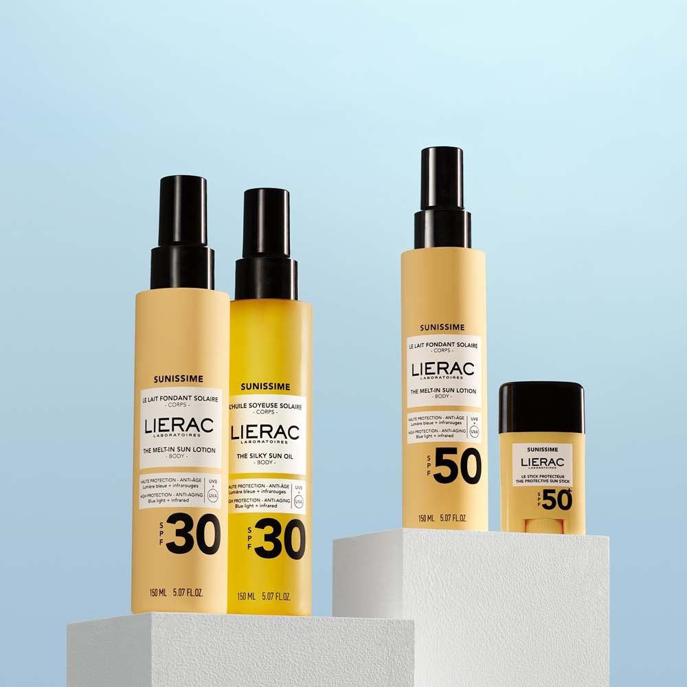 Tre prodotti solari su piedistalli. Due lozioni SPF30, un olio SPF30 e uno stick SPF50. Logo LIERAC visibile.