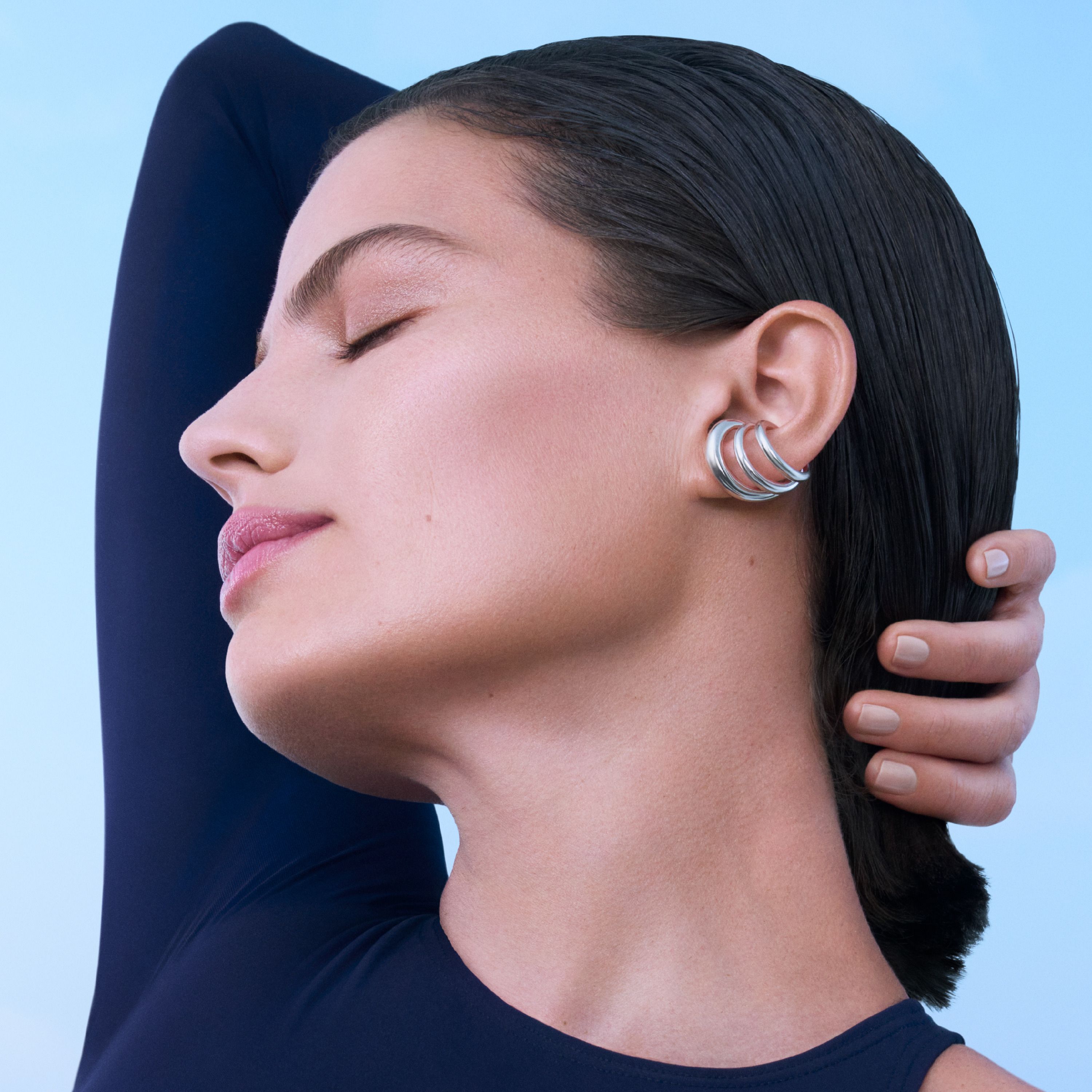 Donna con occhi chiusi e orecchini. Sfondo blu.